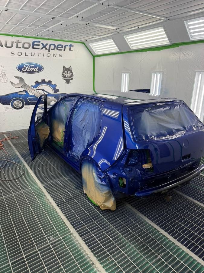 Caroserie de autoturism vopsită în albastru, imediat după aplicarea straturilor în cabina de vopsire